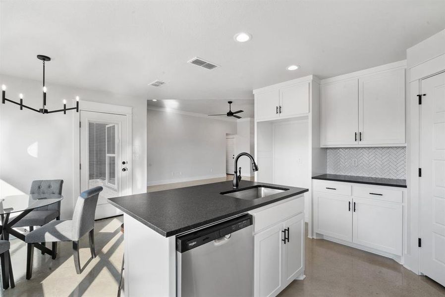 Kitchen featuring pendant lighting, sink, stainless steel dishwasher, and white cabinets