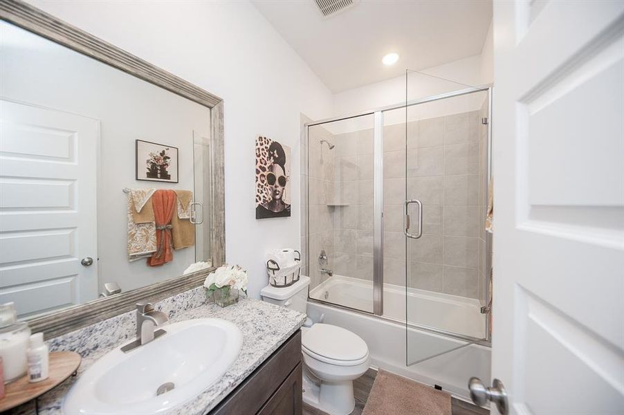 A full bathroom services the front 2 bedrooms.  The seller added a seamless glass door to the shower/tub combo, framed out the mirror, and updated the faucets from builder grade to modern and chic.