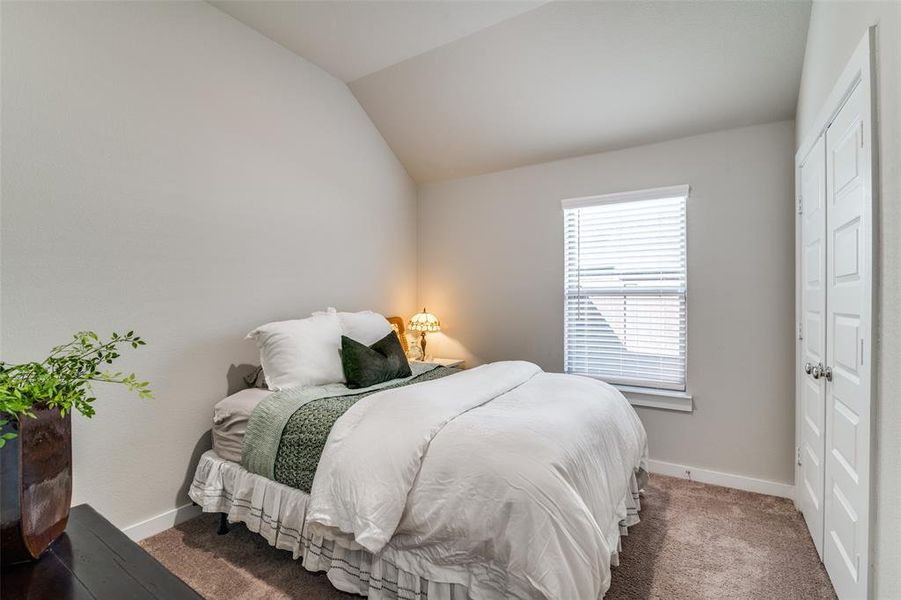 Bedroom with lofted ceiling and dark colored carpet