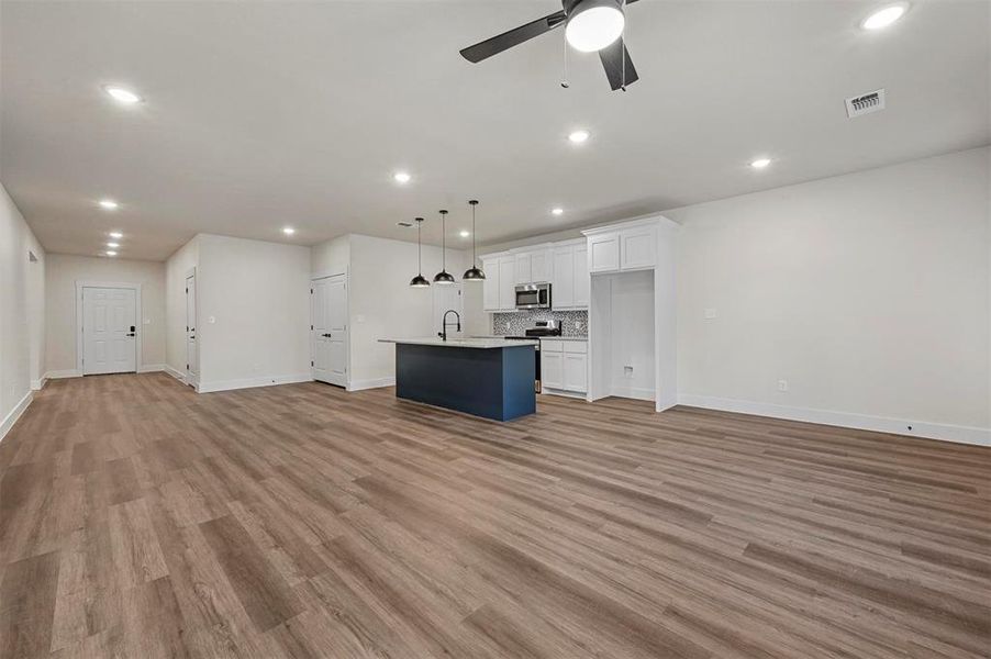 Unfurnished living room with light hardwood / wood-style floors, sink, and ceiling fan