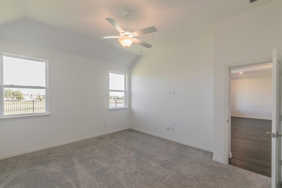 Empty room featuring carpet, lofted ceiling, and ceiling fan