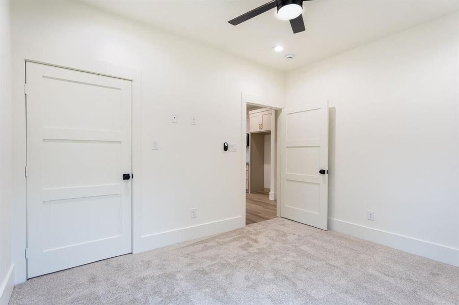 Unfurnished bedroom with ceiling fan and light colored carpet