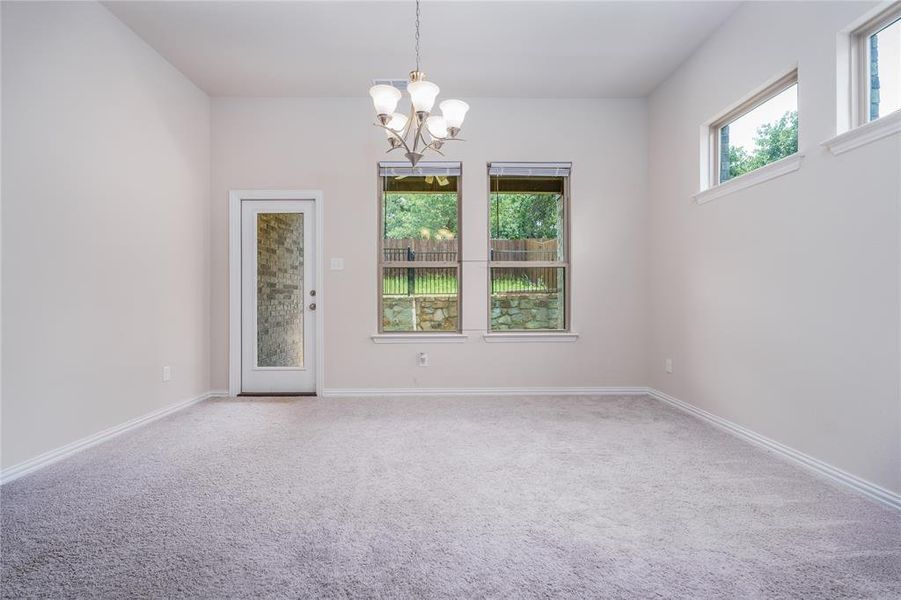 Spare room featuring a notable chandelier and carpet flooring