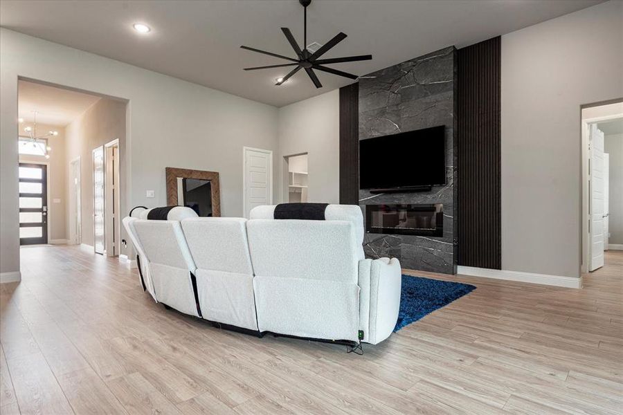 Living room with a large fireplace, light hardwood / wood-style flooring, and ceiling fan