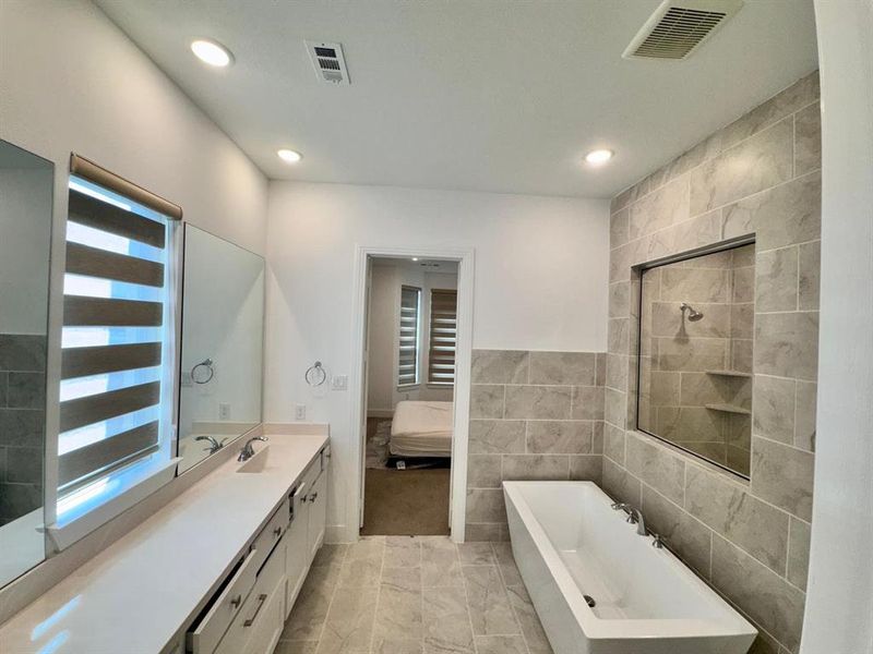 Bathroom with vanity, tile walls, and plus walk in shower