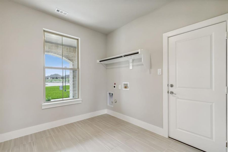 Laundry area featuring washer hookup, hookup for a gas dryer, electric dryer hookup, and light tile patterned floors