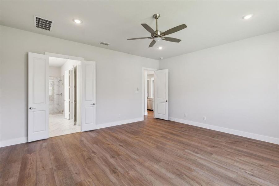 Unfurnished bedroom with connected bathroom, ceiling fan, and hardwood / wood-style floors