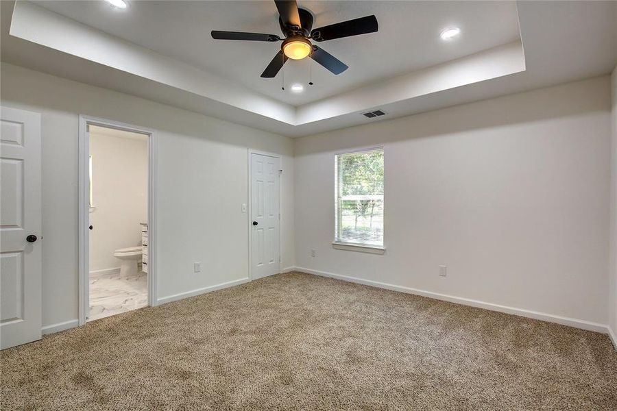 Primary room featuring carpet flooring, ceiling fan, and a raised ceiling