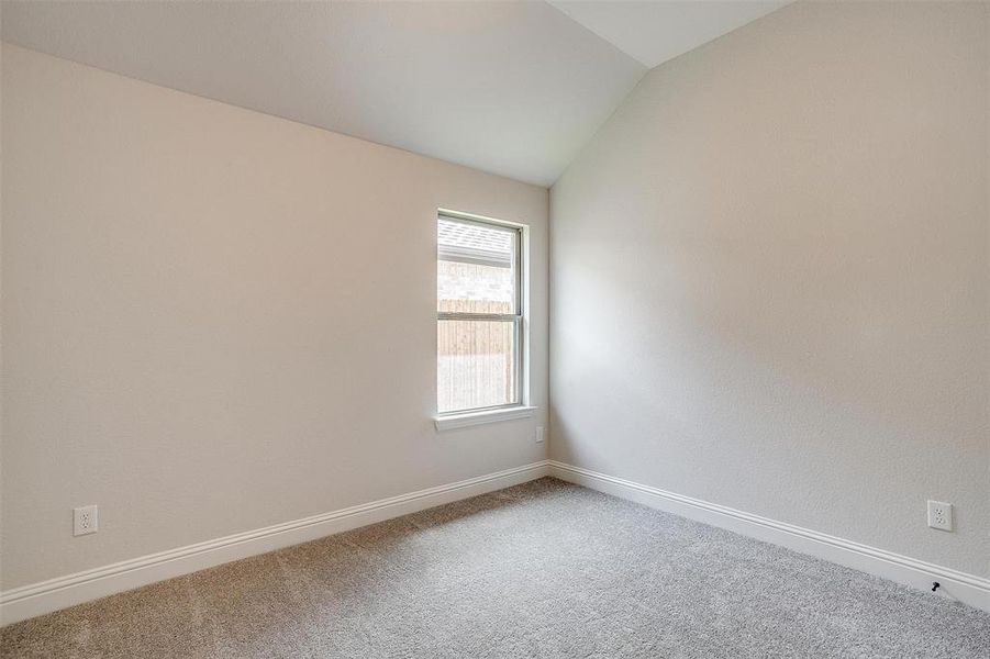 Carpeted empty room with lofted ceiling