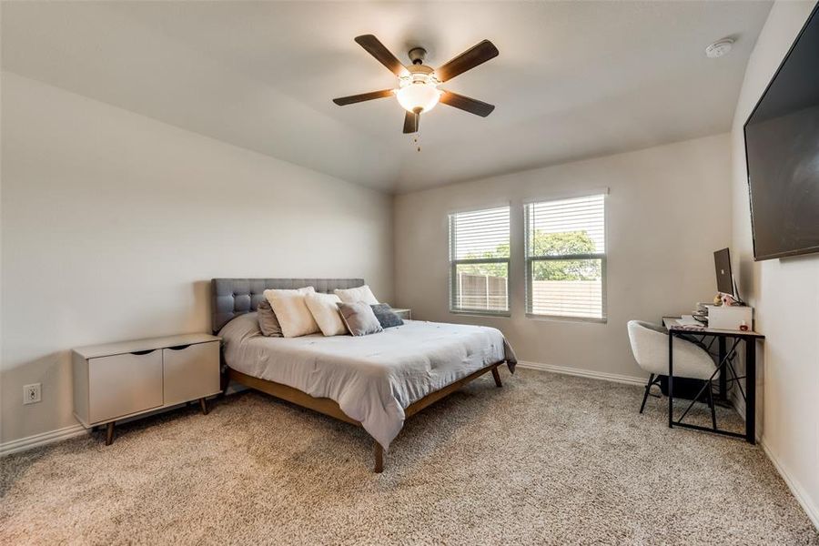 Bedroom featuring ceiling fan, vaulted ceiling, and light carpet