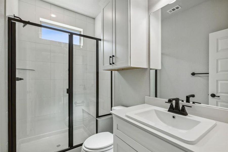 Bathroom featuring vanity, toilet, and an enclosed shower