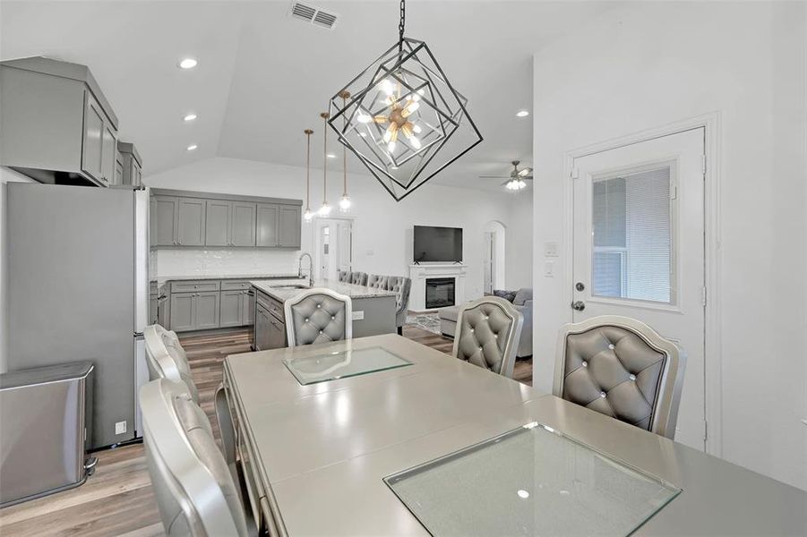 Dining area featuring light hardwood / wood-style flooring, lofted ceiling, sink, and ceiling fan with notable chandelier