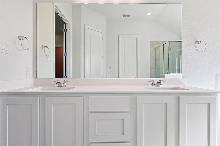 Bathroom with lofted ceiling, a shower with shower door, and vanity