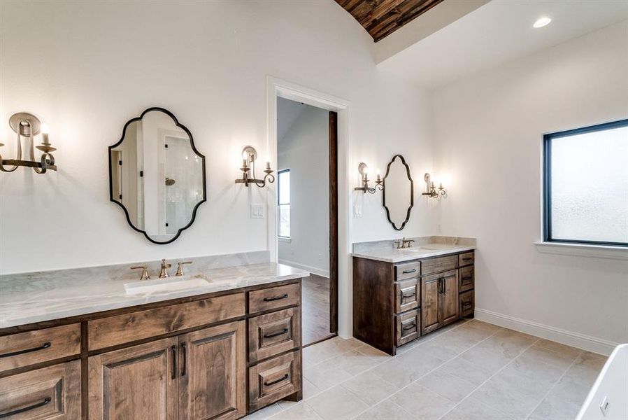 Bathroom featuring tile patterned flooring, vaulted ceiling, vanity, and a healthy amount of sunlight