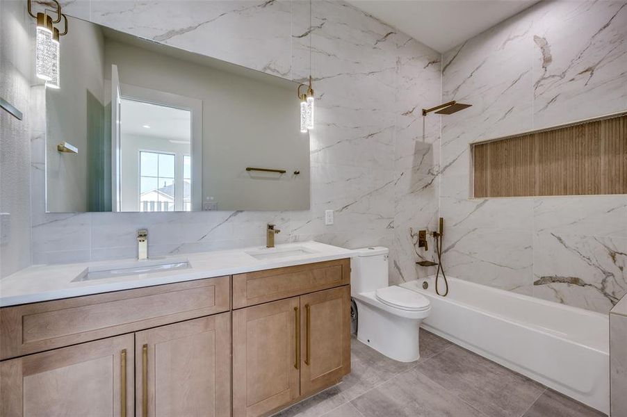 Full bathroom with toilet, bathtub / shower combination, vanity, and tile walls