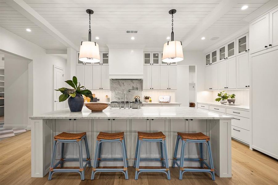 Kitchen featuring a spacious island, decorative light fixtures, light hardwood / wood-style flooring, and white cabinets