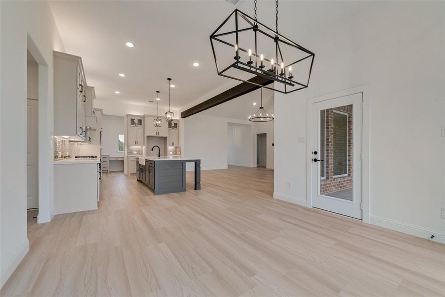 Kitchen featuring a kitchen breakfast bar, pendant lighting, an island with sink, sink, and light wood-type flooring