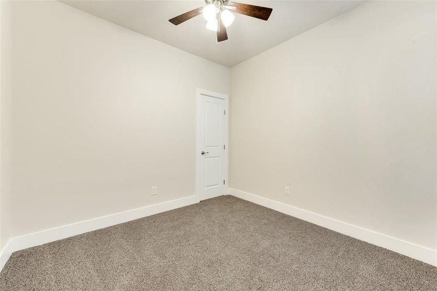 Carpeted spare room featuring ceiling fan