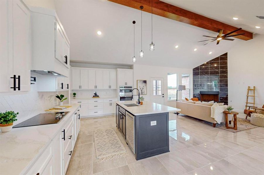 Kitchen with white cabinetry, hanging light fixtures, a center island with sink, and beamed ceiling