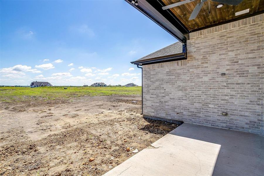 View of yard featuring a patio, ceiling fan, and a rural view