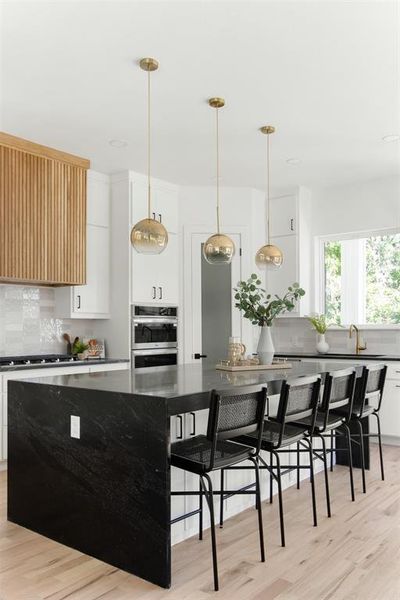 Kitchen featuring a center island, backsplash, double oven, and light hardwood / wood-style flooring