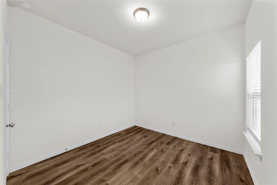 Empty room featuring dark wood-type flooring and a wealth of natural light