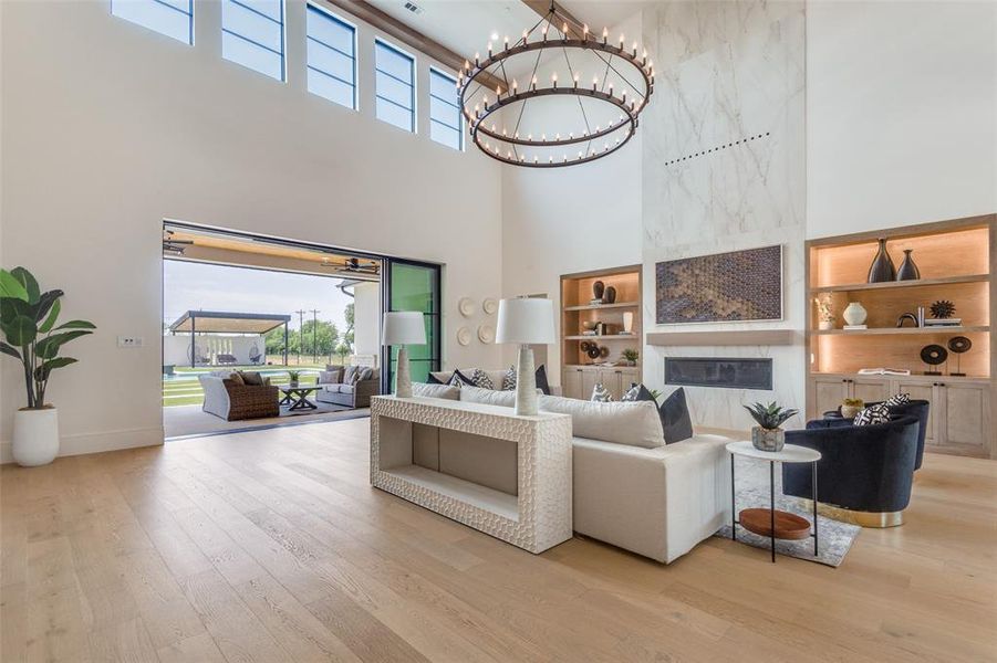 Living room featuring a high ceiling, a notable chandelier, light hardwood / wood-style flooring, and a high end fireplace