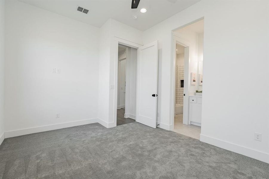 Unfurnished bedroom with light carpet, connected bathroom, and ceiling fan