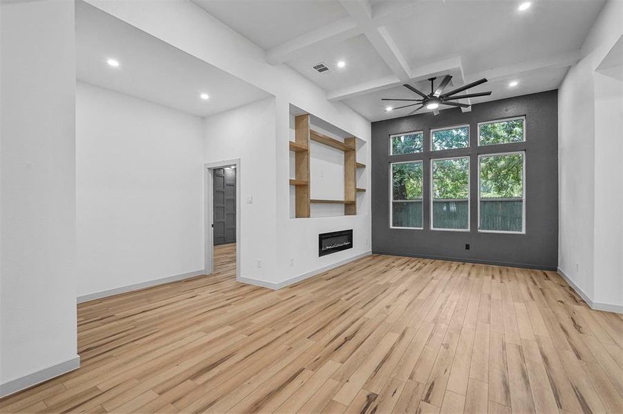 Unfurnished living room featuring coffered ceiling, ceiling fan, beam ceiling, and light hardwood / wood-style flooring