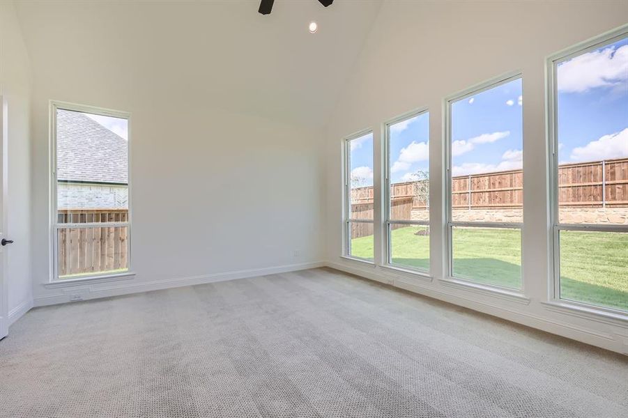 Unfurnished room featuring high vaulted ceiling, ceiling fan, and light colored carpet