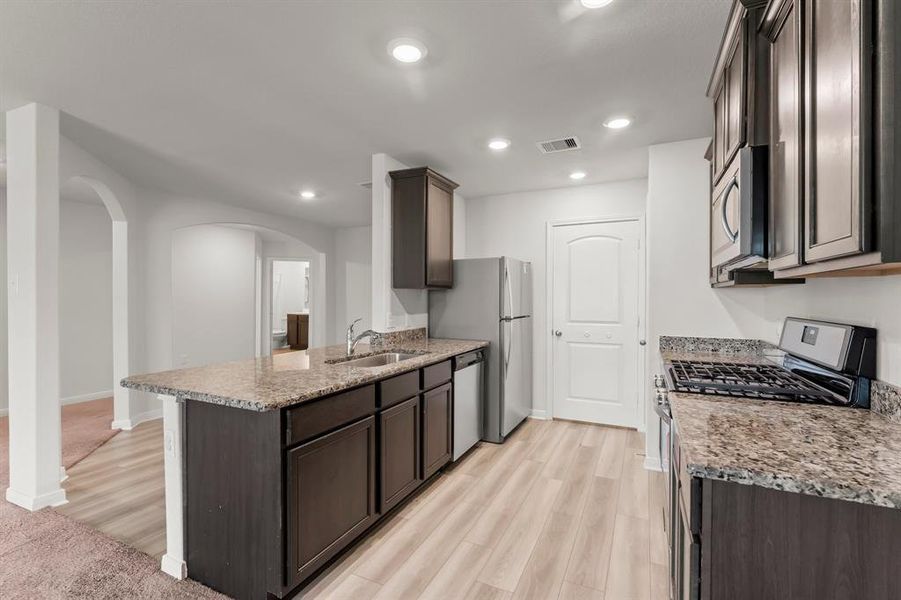 This elegant kitchen boasts plenty of cabinets and sleek granite counter top workspace.