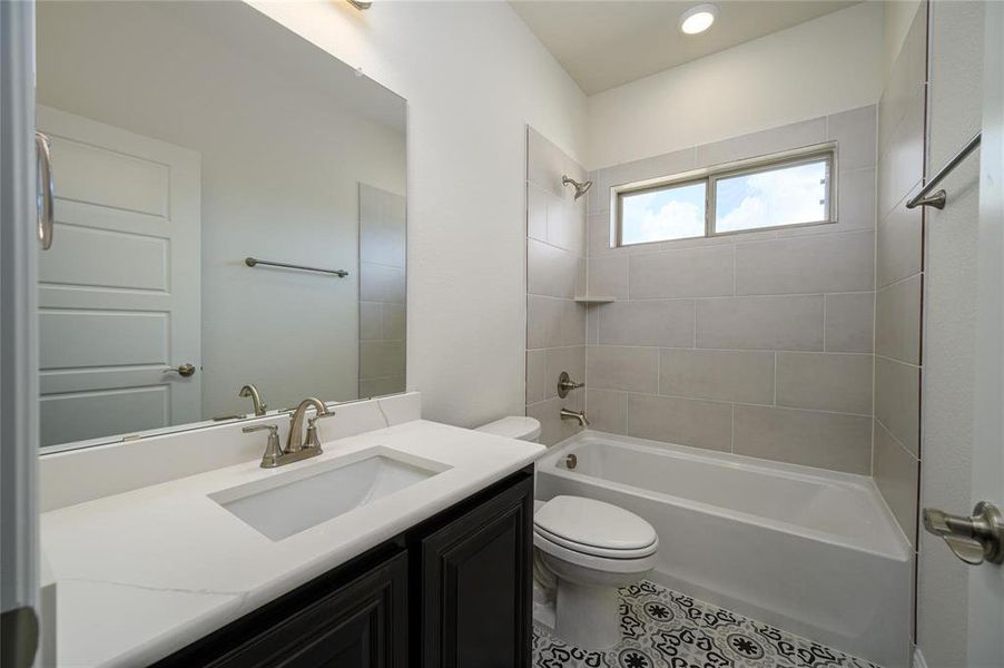 Full bathroom with tile patterned flooring, toilet, vanity, and tiled shower / bath