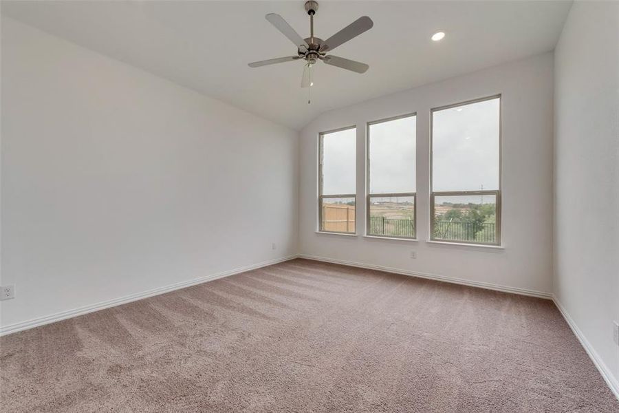 Carpeted empty room with ceiling fan and vaulted ceiling