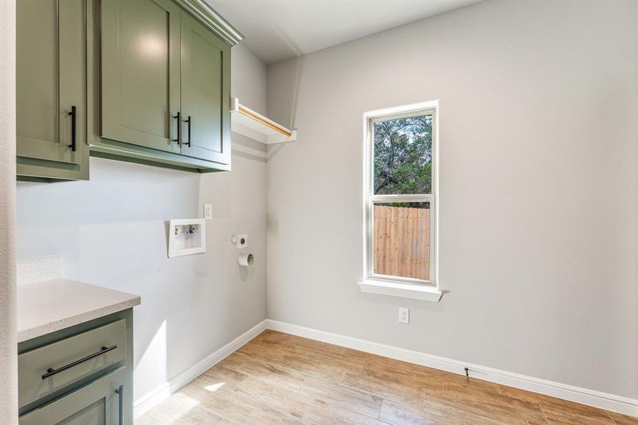 Laundry room featuring cabinets, light wood-type flooring, hookup for an electric dryer, and hookup for a washing machine