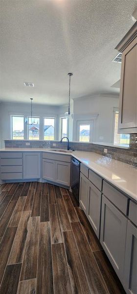 Kitchen has dark hardwood / wood-style floors, pendant lighting, and gray cabinetry