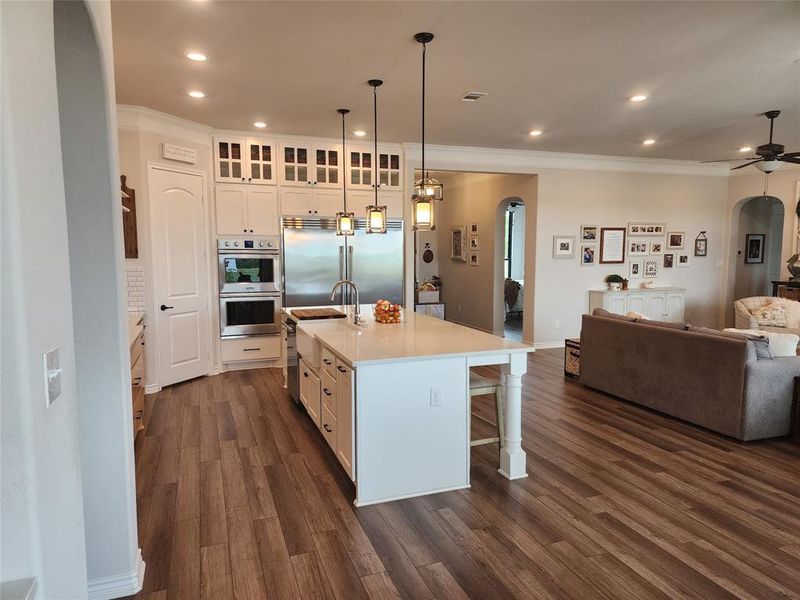 Kitchen with a kitchen breakfast bar, appliances with stainless steel finishes, dark hardwood / wood-style floors, and a kitchen island with sink