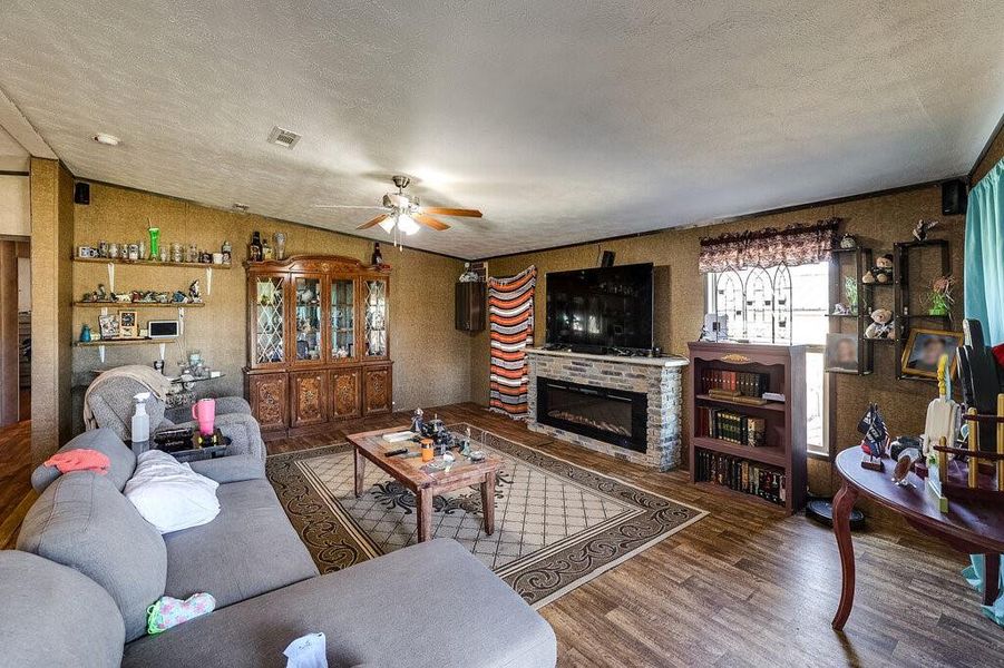 Living room with a textured ceiling, wood-type flooring, lofted ceiling, and ceiling fan