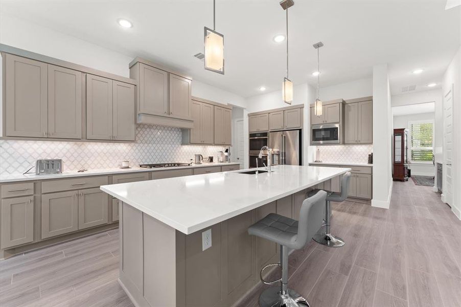 Custom cabinetry, pendant lighting, and a sleek modern tile backsplash add elegance to the space