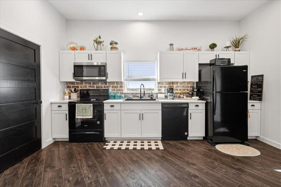 Kitchen featuring sink, white cabinets, tasteful backsplash, black appliances, and dark hardwood / wood-style floors