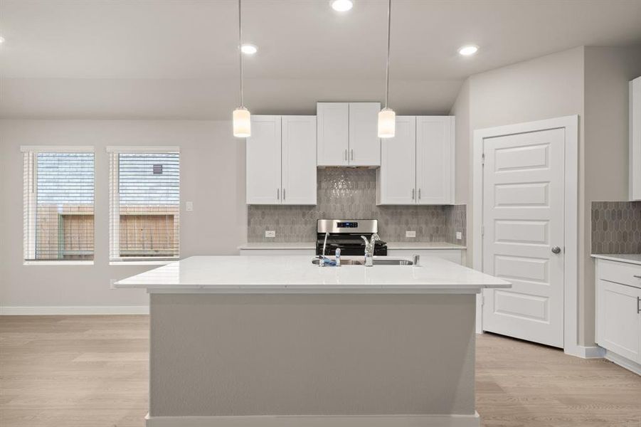 An additional view of the Gourmet Kitchen with pendant lighting, custom backsplash, and oversized kitchen island w/ breakfast bar.