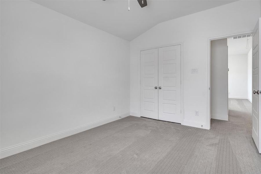 Unfurnished bedroom featuring lofted ceiling, carpet floors, and ceiling fan