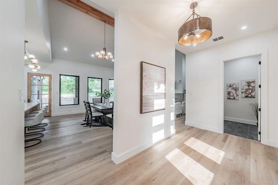 Entrance foyer featuring beam ceiling, featuring blonde plank, wood-like luxury vinyl floors.