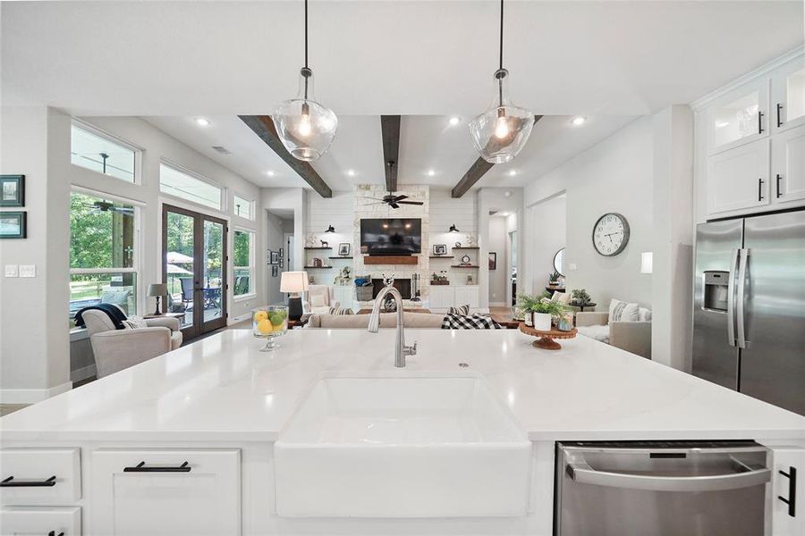 The centerpiece of this stunning kitchen is the oversized island with a sleek Quart countertop, upgraded sink, custom pull-outs, bougie overhead lighting, and a convenient breakfast bar on the opposite side.
