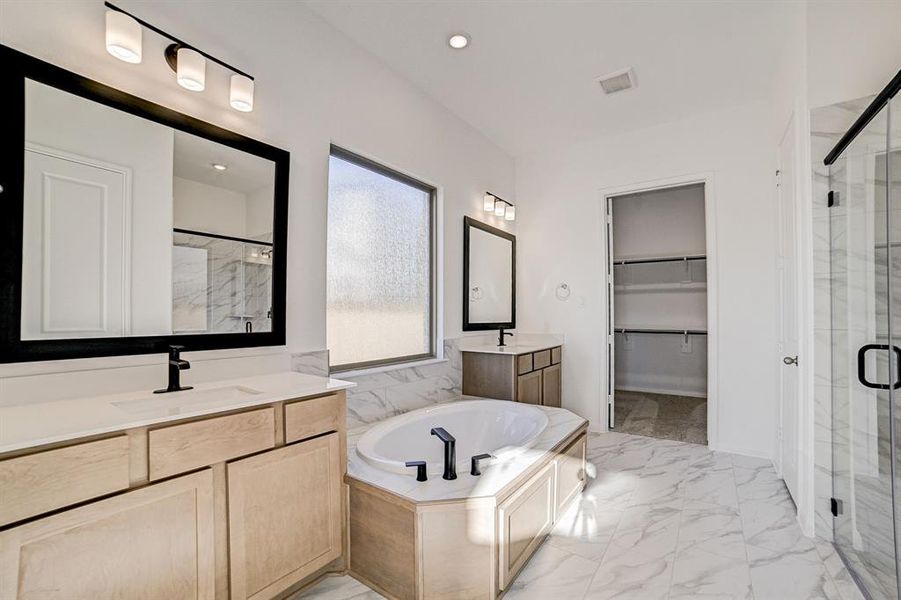 Gorgeous upgraded selections grace the primary bathroom. Dual sinks, large soaking tub and separate glass shower, walk through to the primary closet.