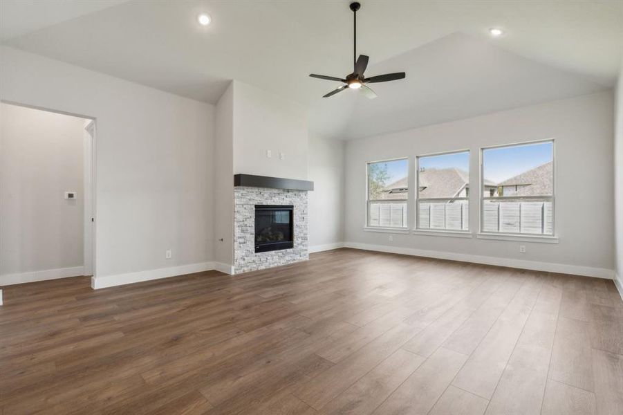 Unfurnished living room featuring a fireplace, high vaulted ceiling, wood-type flooring, and ceiling fan