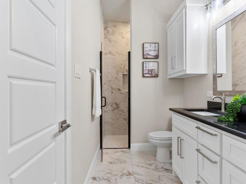 Bathroom with a tile shower, vanity, and toilet