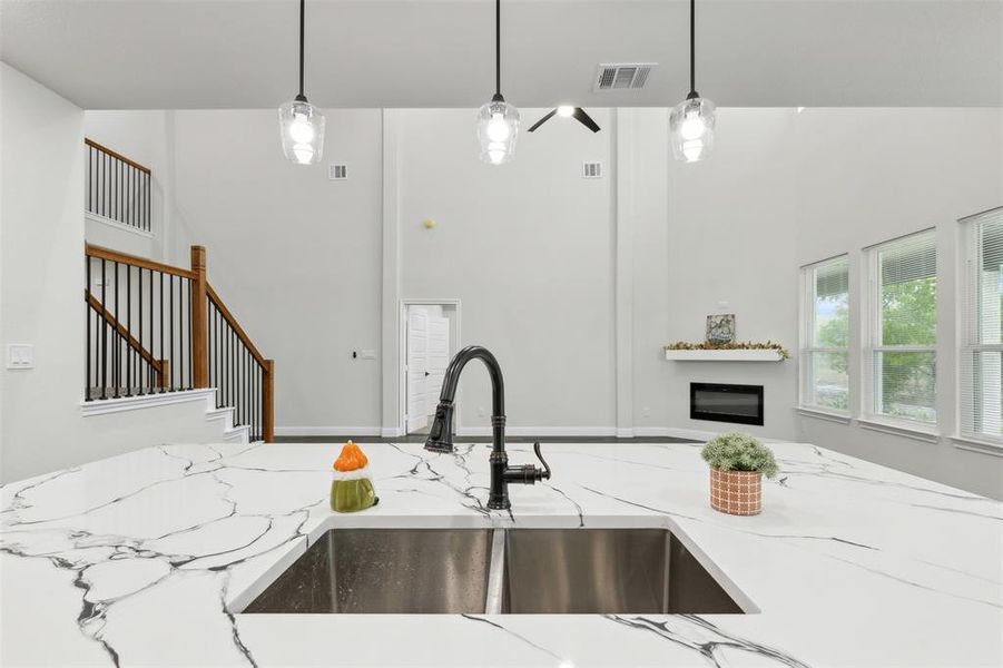 Kitchen with sink, light stone countertops, and hanging light fixtures