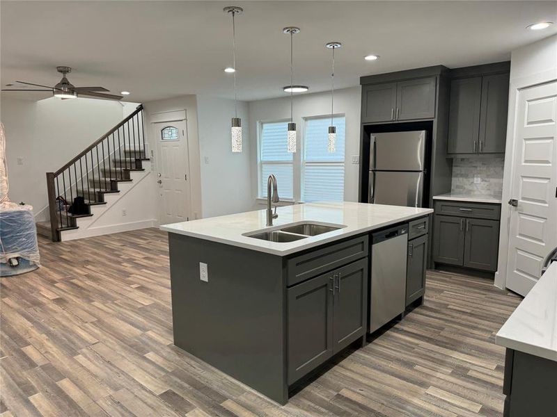 Kitchen with gray cabinetry, dark wood-type flooring, stainless steel appliances, sink, and ceiling fan