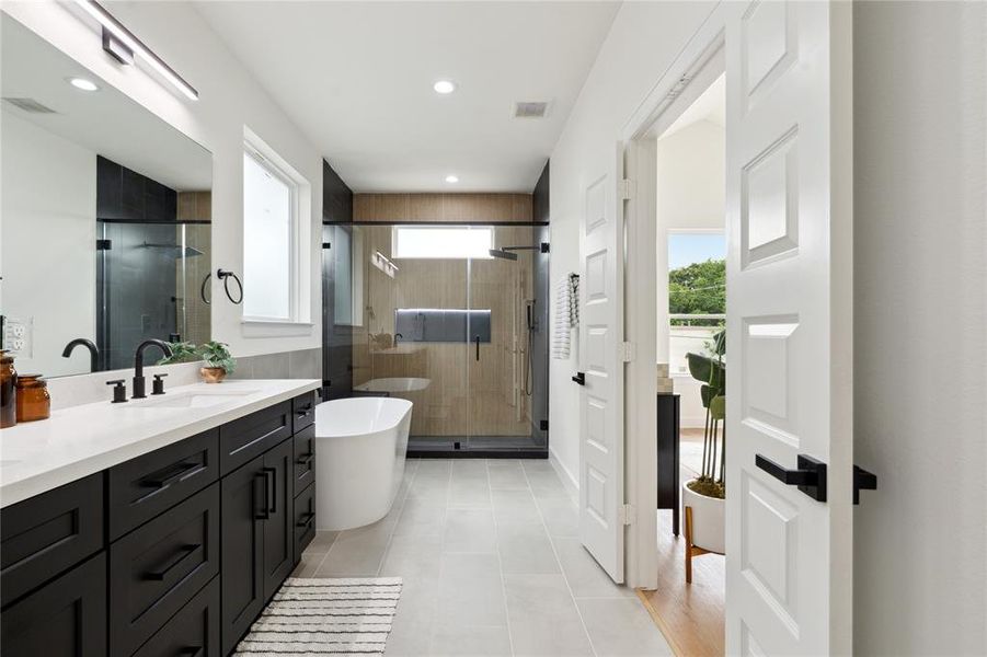 Experience luxury in this primary ensuite, complete with his-and-hers sinks, a standalone soaking tub, and a frameless walk-in shower that exudes sophistication and style.