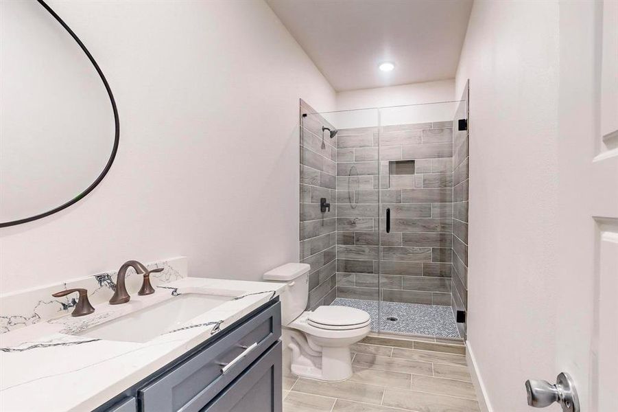 Bathroom with vanity, toilet, and a shower with shower door